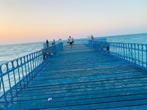 a group of people standing on a pier near the ocean at شاليه بقريه جرين بيتش الساحل الشمالي 4 غرف تشطيب السنه لوكس in El Alamein