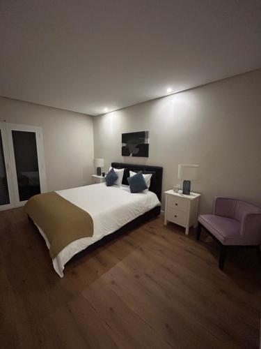 a bedroom with a large bed and a pink chair at The Place to Stay ! in Póvoa de Santa Iria
