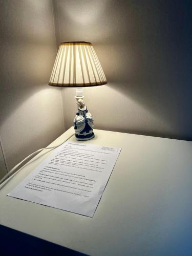 a lamp sitting on top of a table with a paper at Cozy room surrounded by nature in Falun