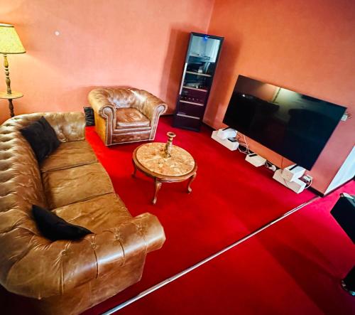 a living room with a leather couch and a television at "Instant Zen" Chambre double - 15 min Merignac airport et Bordeaux in Saint-Médard-en-Jalles