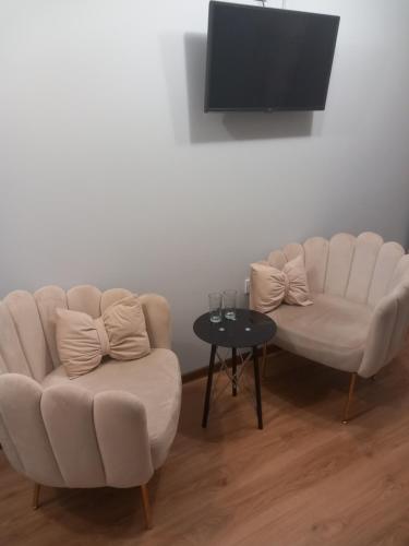 a living room with two white chairs and a tv at Стаи за гости - Цветето на Ангела in Bankya