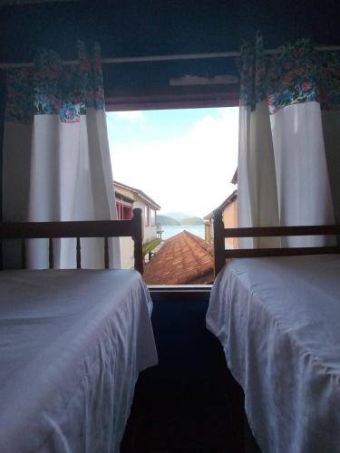 two beds in a bedroom with a view of the ocean at hostel Boa Onda Trindade in Paraty