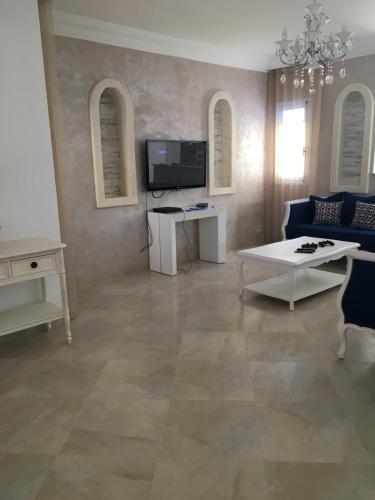 a living room with a blue couch and a tv at La Villa Bleue Djerba Houmt Souk in Houmt Souk