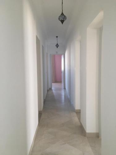 an empty hallway with white walls and a chandelier at La Villa Bleue Djerba Houmt Souk in Houmt Souk