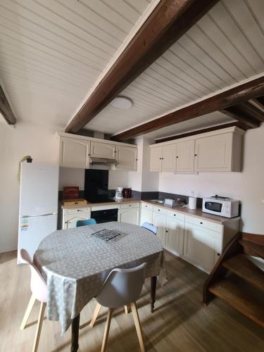 a kitchen with a table with chairs and a refrigerator at Maison auvergnate entièrement rénovée in Brioude