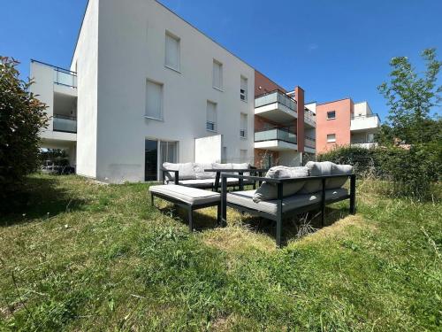 tre panche sedute sull'erba di fronte a un edificio di Garden space - T4 - Airport - Garden - Tram a Blagnac