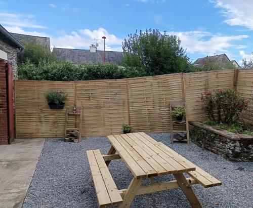 a wooden picnic table in a backyard with a fence at Chez Colette in Aucey-la-Plaine