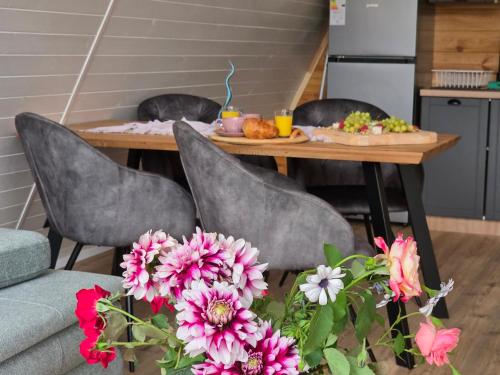 a table with two chairs and a table with flowers at Api Aframe in Avrig