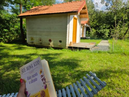 a person holding a book in front of a house at Api Aframe in Avrig