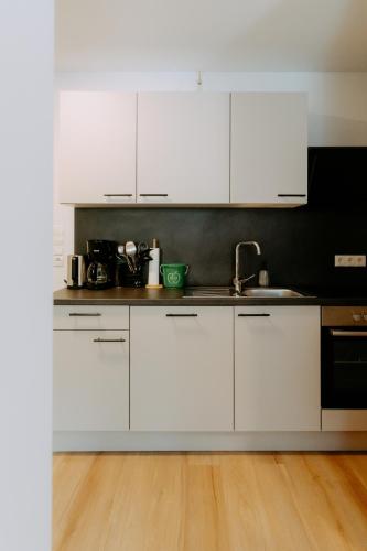 a white kitchen with white cabinets and a wooden floor at Kupferdachl in Sankt Lambrecht