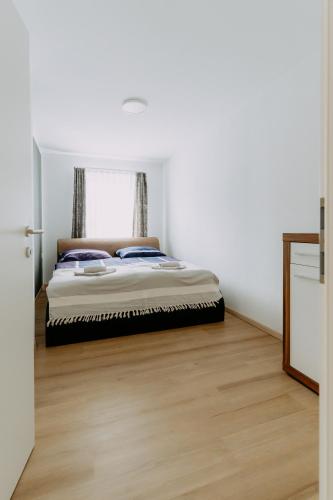 a bed in a white room with a wooden floor at Kupferdachl in Sankt Lambrecht