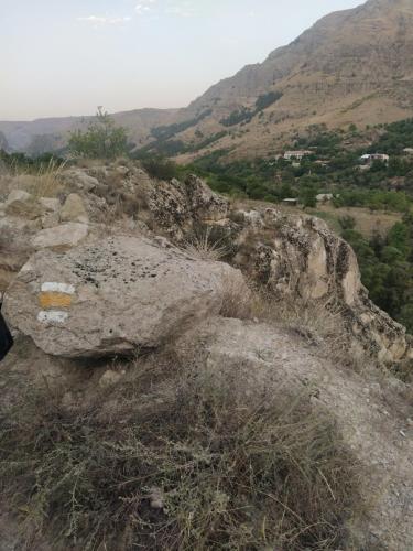 a large rock on a hill with mountains in the background at Vardzia Old Village in Vardzia