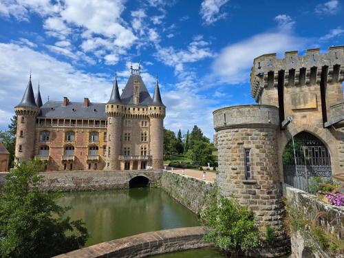 a castle with a bridge in front of a body of water at La maison du père Bellessort in Régnié