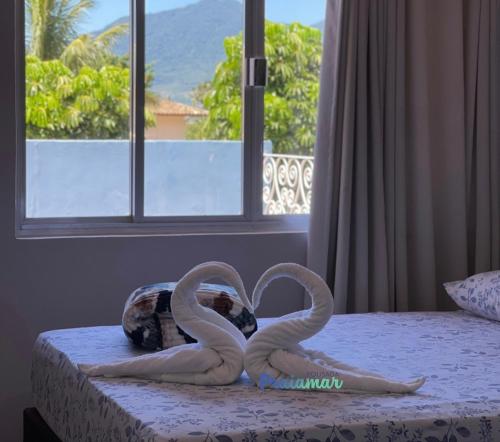 two sculptures of swans making a heart on a bed at Pousada Praiamar in São Sebastião