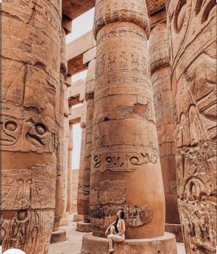 a woman sitting on a pillar in an ancient building at Elbess For Tourism in Jazīrat al ‘Awwāmīyah