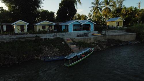 a boat in the water next to a house at Don Som Riverside Guesthouse in Don Som