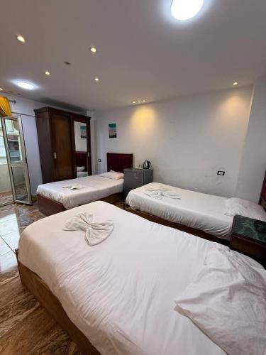 a hotel room with three beds with white sheets at Middle East pyramids veiw &jacuzzi in Cairo