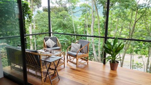 2 sillas y una mesa en un balcón con árboles en River Lodge, en Uvita