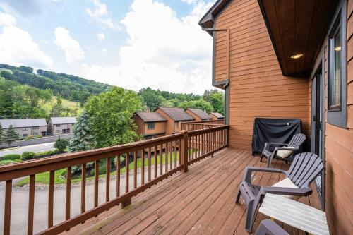 a deck with two chairs and a bench on a house at 3 Bedroom Townhouse Across from HoliMont in Ellicottville