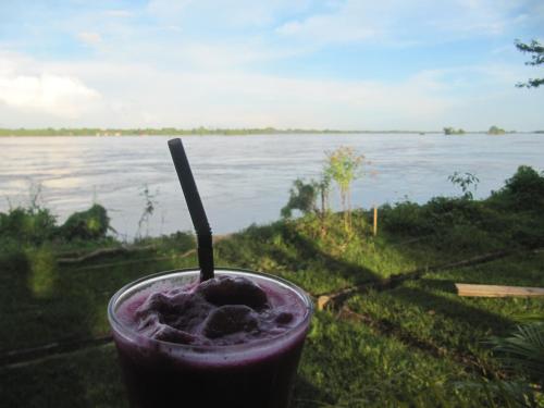 a drink sitting on the grass with a view of the water at Don Som Riverside Guesthouse in Don Som