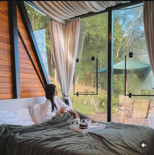 a woman sitting on a bed looking out a window at Audaz 1 in Água Boa