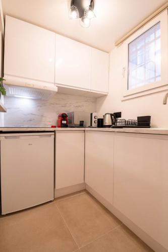 a white kitchen with white cabinets and appliances at Studio Place Masséna in Nice