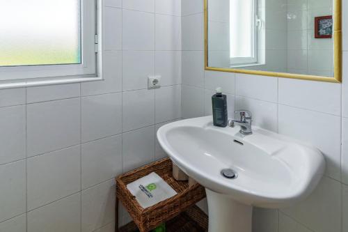 a white bathroom with a sink and a mirror at Casas do Porto in Mosteiros