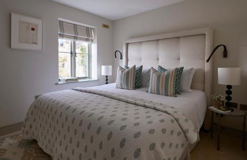 a white bedroom with a large bed with a large headboard at Stunning Cotswolds guest house in Chadlington