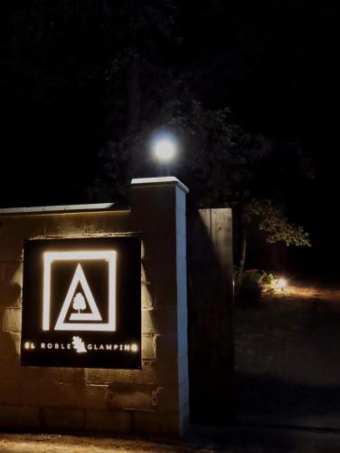 a sign on a wall at night with a light at El Roble Glamping - Cabaña Alpina - Pet Friendly in Lagunilla