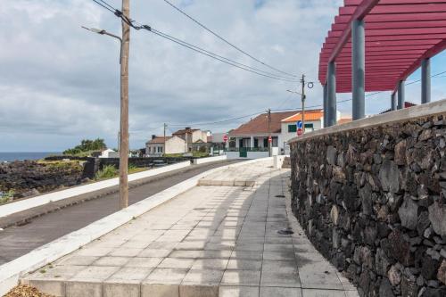 a stone wall and a sidewalk next to a street at Casas do Porto in Mosteiros