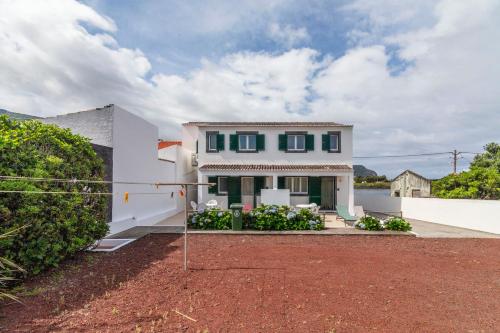 a white house with green windows and a yard at Casas do Porto in Mosteiros