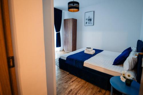 a bedroom with a bed with blue sheets and a table at Complex Omnia - Apartamente Husi in Huşi