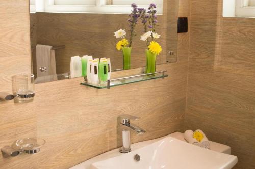 a bathroom with a sink and a mirror and flowers at Shalom Residence Kandy in Kandy