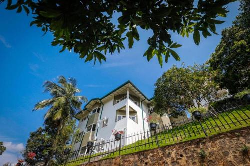 a white house with a fence and a palm tree at Shalom Residence Kandy in Kandy