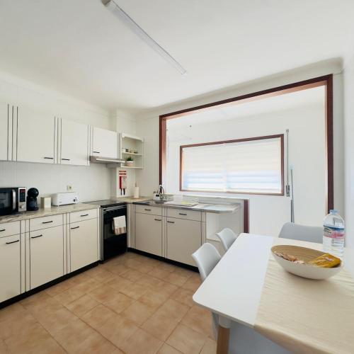 a kitchen with white cabinets and a table with a bowl on it at Recanto das Areias - 2-bedroom apartment 5 minutes from the beach in Torreira