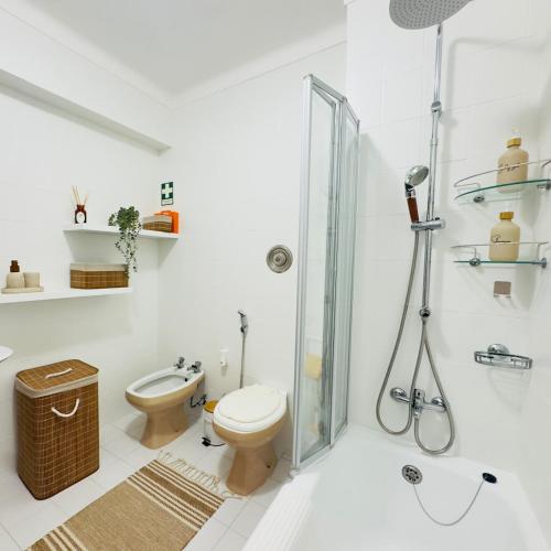 a white bathroom with a toilet and a shower at Recanto das Areias - 2-bedroom apartment 5 minutes from the beach in Torreira