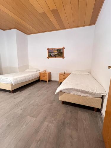 two beds in a room with white walls and wooden ceilings at Komfortable Ferienwohnung Monteuerzimmer in Lauenau