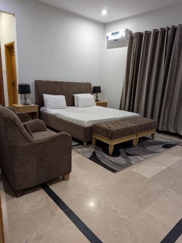 a bedroom with a bed and a couch and a chair at Signature Suite 2BR At Country Club Resorts Balakot in Bālākot