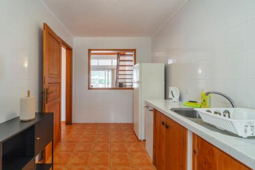 a kitchen with a sink and a refrigerator at Casas do Porto in Mosteiros