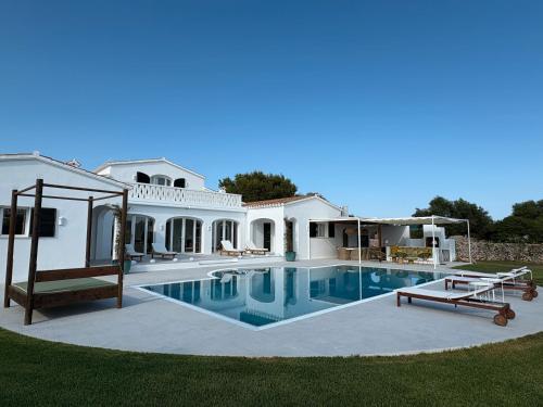 a large white house with a swimming pool at Villa Estrellita Sant Lluis in Sant Lluis