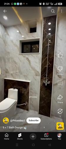 a bathroom with a white toilet and a marble wall at हर्षवाणी होम स्टे Harshvanee Home Stay in Lucknow