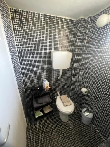 a bathroom with a toilet and a tiled wall at Maison De La Mer in Isthmia
