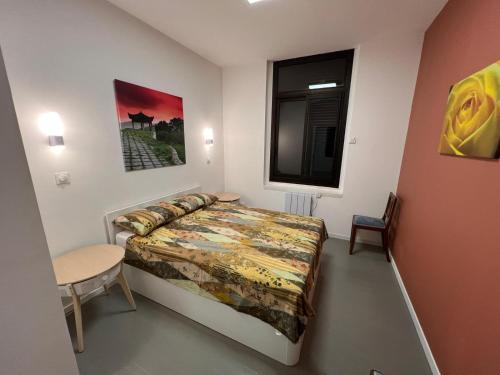 a bedroom with a bed and a table and a window at Apartment - Abbaye aux Dames, reserved parking in Saintes