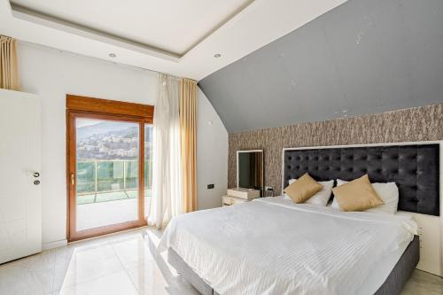 une chambre avec un grand lit et une grande fenêtre dans l'établissement Alanya Luxury Villas 1, à Alanya