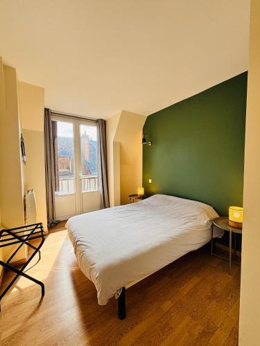 a bedroom with a large bed with a green wall at Le Jeanne d'Arc - Appartements meublés in Gien