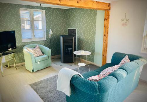 a living room with a blue couch and two chairs at Ferienhaus Emma in Langelsheim