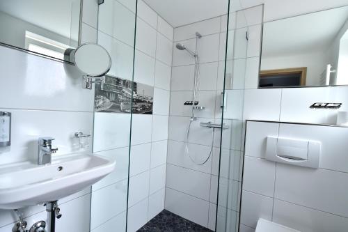 a white bathroom with a shower and a sink at GT3 Hotel in Honerath