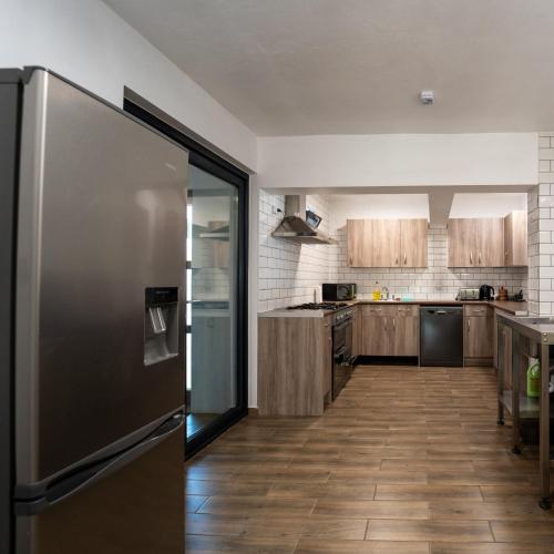 a kitchen with a stainless steel refrigerator and wooden cabinets at Pensiunea Plaiul Domnesc Runcu in Runcu