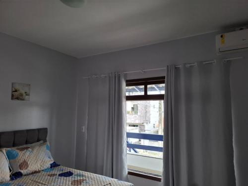 a bedroom with a bed and a window with a view at Bela e Aconchegante in Bombinhas