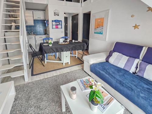 una sala de estar con un sofá y una mesa en Duplex vue mer, balcon, parking privé, en Cabourg